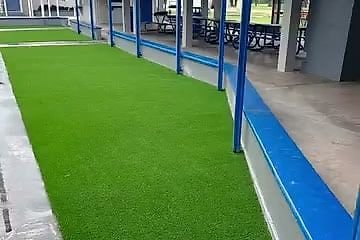 El mismo pasillo con grama artificial verde a lo largo de las columnas azules.